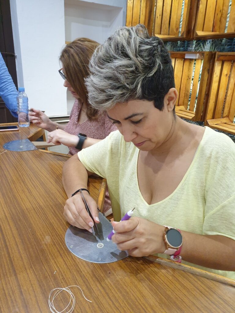 Participante del taller montando con pinzas una pieza de filigrana de plata